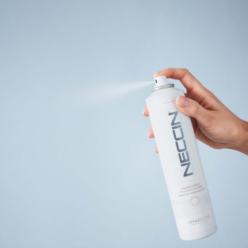 Eine Hand sprüht eine weiße Dose mit 'NEOCIN'-Aufschrift gegen einen hellen Hintergrund.