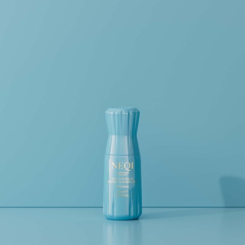 Een lichtblauwe fles staat op een bijpassende blauwe achtergrond met gouden tekst op de fles.