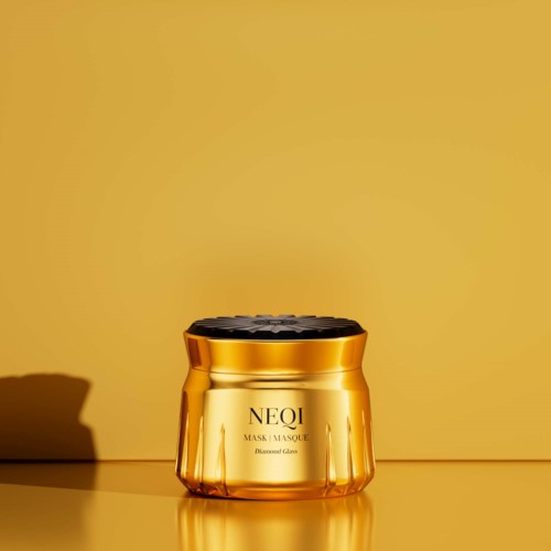 Gold-colored jar of NEQI Diamond Glass mask with black lid, placed on a yellow surface with a yellow background.