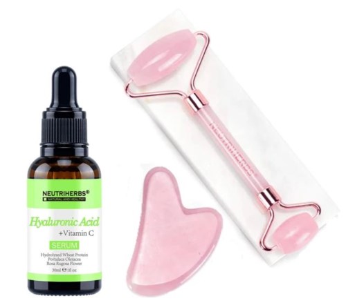 A bottle of hyaluronic acid serum, a pink jade roller, and a pink gua sha tool.
