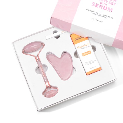 Et rosa hudpleiesett som inkluderer en rulle, et hjerteformet element, og Vitamin C-serum i en eske.