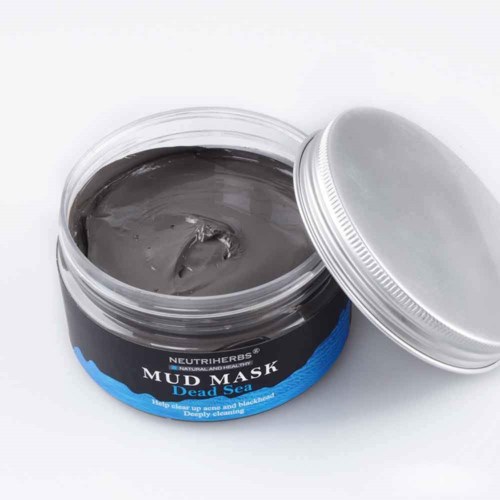 En burk med Dead Sea-maske med ett silverlock, delvis öppet, som visar mörkgrå lera inuti.