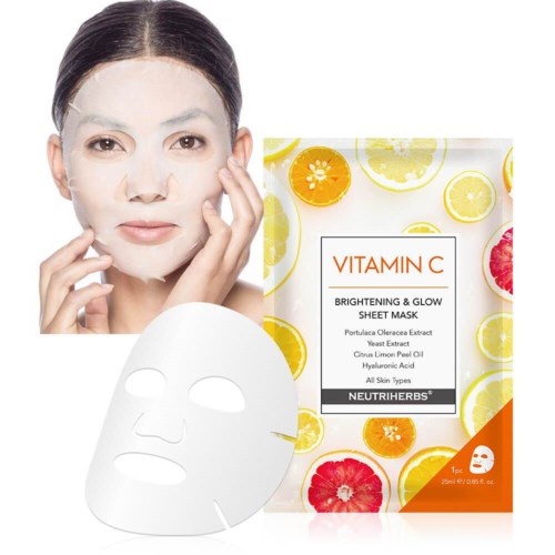 Een vrouw met een gezichtsmasker die haar huid verheldert. Naast haar ligt een vitamine C-sheet masker met citrusafbeeldingen.