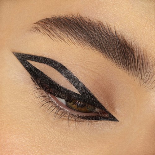 Nærbillede af en person med kraftig sort og sølv øjenskygge, skarp eyeliner og velplejede øjenbryn.