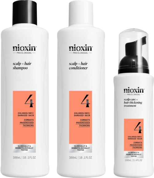 Tre flasker Nioxin hårplejeprodukter til beskadiget hår, inklusive shampoo, balsam og behandling, med orange etiketter.