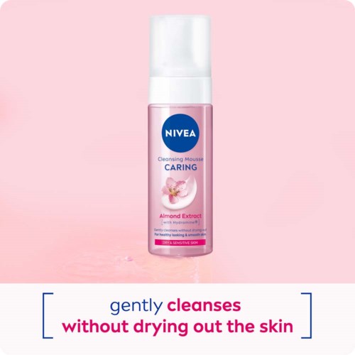 A pink bottle of Nivea Cleansing Mousse, almond extract, for sensitive skin, with a white cap, against a pink background.