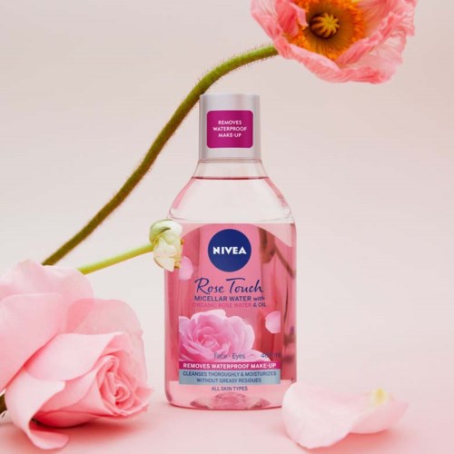 En lyserød flaske med Nivea Rose Touch Micellar Water med en rose og blomsterblad rundt.