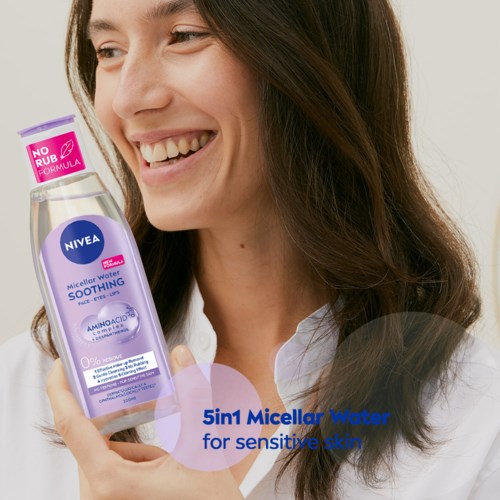Nainen hymyilee ja pitää kädessään Nivea Micellar Water -kokta, edistäen ihohoitoa herkkäiholle.