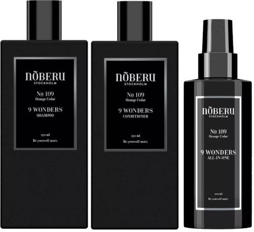 Tre svarta flaskor med vita etiketter för schampo, balsam och allt-i-ett-produkt från Nöberu Stockholm.
