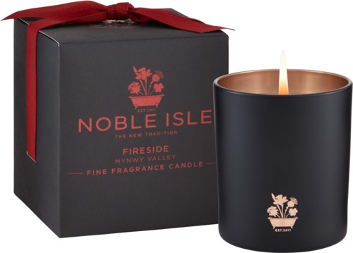 En svart ljuslykta med rosdesign, bredvid en svart box med rött lock och band, märkt Noble Isle Fireside.