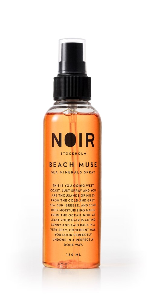 En klar sprayflaske med orange væske, mærket 'NOIR Stockholm Beach Muse Sea Minerals Spray.'
