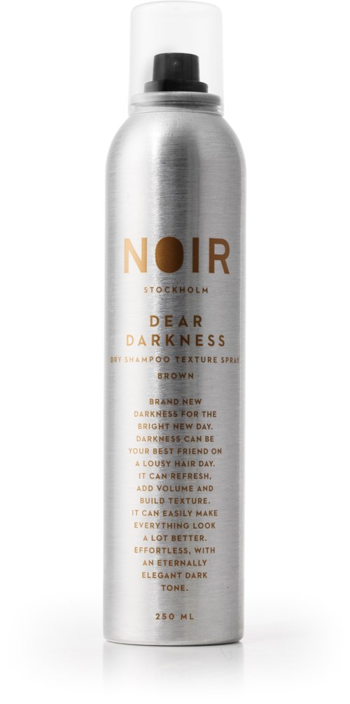 En silver sprayflaska märkt 'NOIR'. Den är en hårtexturspray med brunt färg, avsedd att tillföra volym och skapa struktur.