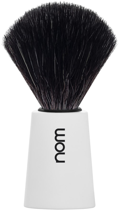 En makeup-borste med svarta borst och ett vitt handtag märkt 'nom'.