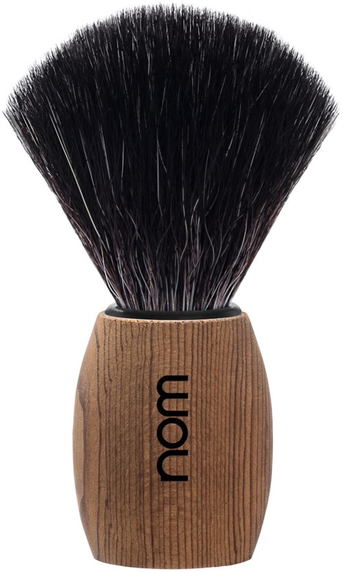 En makeupborste med ett trähantaget märkt "nom" och svarta borst.