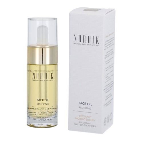 En ansiktsolja i en tydlig flaska med pump, bredvid en vit förpackning. Etiketten säger Nordic Face Oil Restoring.
