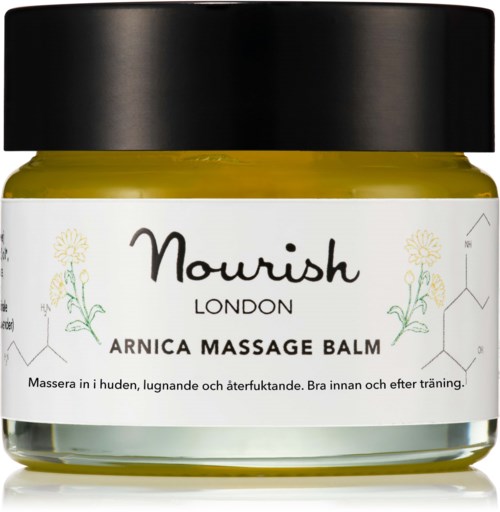 Nourish London Arnica Massage Balm w słoiku, przeznaczony do relaksacji i odnowy skóry, z czarnym wiekiem i kwiatowym wzorem.
