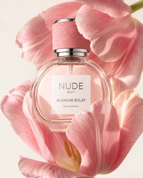 Eine runde Glas-Parfümflasche mit rosa Deckel, umgeben von rosa Blütenblättern.