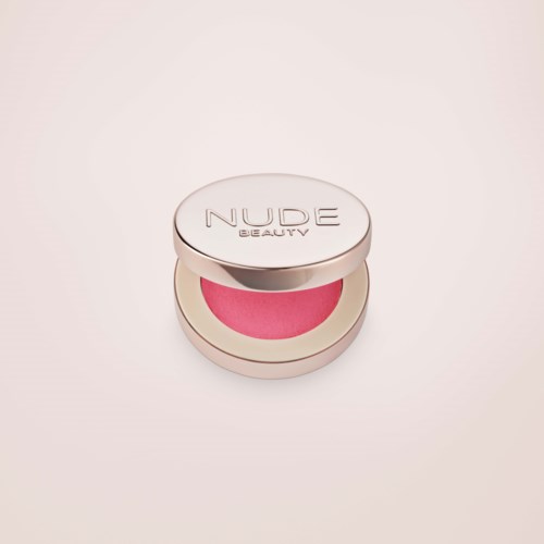 En rund makeup-beholder med pink blush indeni og sølv låg mærket 'NUDE BEAUTY'.