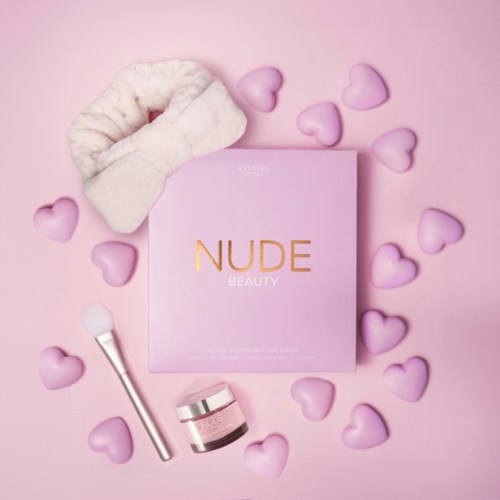 Lyserødt stykke med 'NUDE BEAUTY' mærket, skønhedsredskaber og lilla hjerter på lyserødt baggrund.