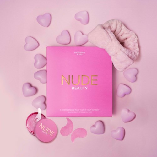 Een roze doos met 'NUDE BEAUTY' eromheen hartvormige snoepjes en een pluizige haarband.