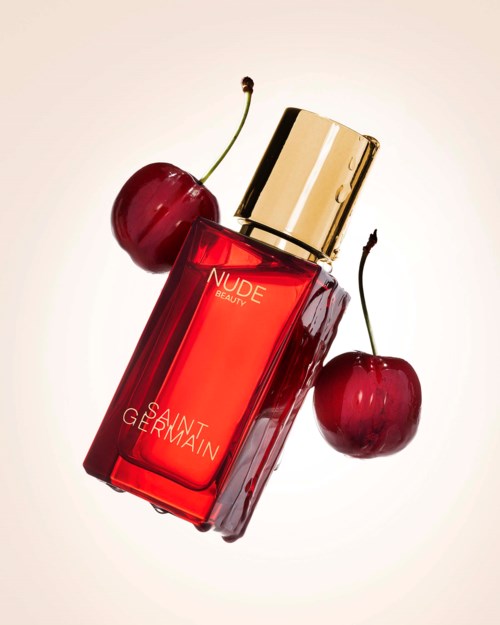 A red perfume bottle labeled  Nude Beauty with two cherries beside it.