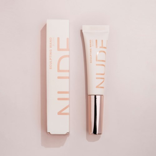 En tube og eske med hudpleieprodukt med minimalistisk design og myke rosa nyanser.