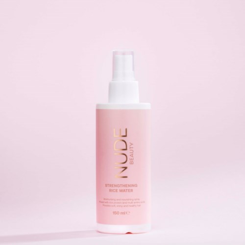 En rosa flaske med hvit pumpe, merket 'LUDE Beauty Strengthening Rice Water' for hudpleie.