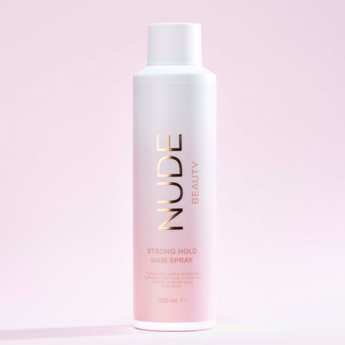 A white bottle with pink and gold text for NUDGE Beauty's strong hold hair spray set against a light pink background.