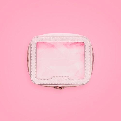 En liten vit väska med genomskinlig framsida, placerad på rosa bakgrund.
