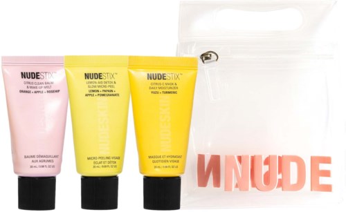 Tre små tuber med hudvårdsprodukter och en vit väska med röd "NUDE"-text.