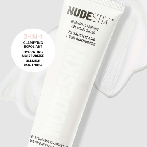 Eine weiße Tube mit 'NUDESTIX' Beschriftung, daneben ein klarem Wasserglas.