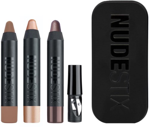 Tre makeuppennor i olika nyanser, ett litet verktyg och ett svart fodral med 'NUDESTIX' skrivet på.