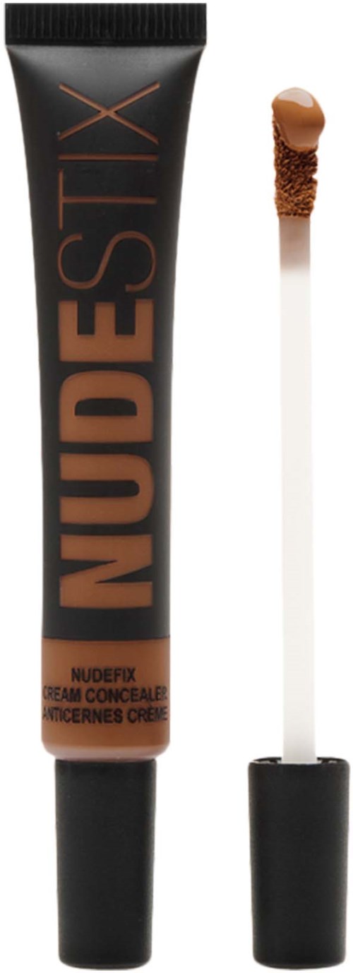 En concealer-rör med orden "NUDESTIX" och en liten applikatorborste med brunt produkt.
