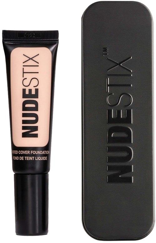 Ein Foundation-Tube mit NUDESTIX-Branding und eine schwarze rechteckige Dose daneben.