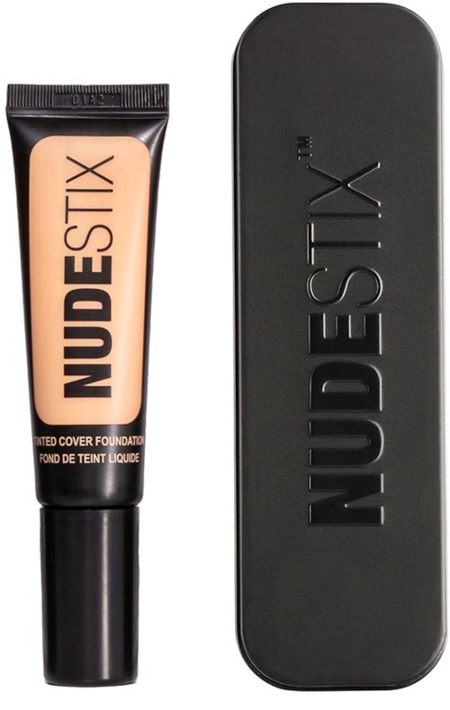 Eine Tube Flüssig-Foundation neben einer schwarzen Kompaktbox, beide mit 'NUDESTIX' beschriftet.