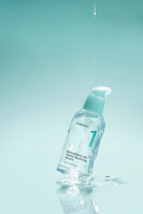 A glass bottle with water in it, labeled with a number and text, standing on a reflective surface.