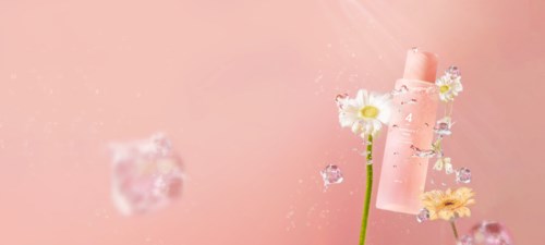 Lys rosa bakgrunn med blomster og en rosa rulle, svevende i luften.