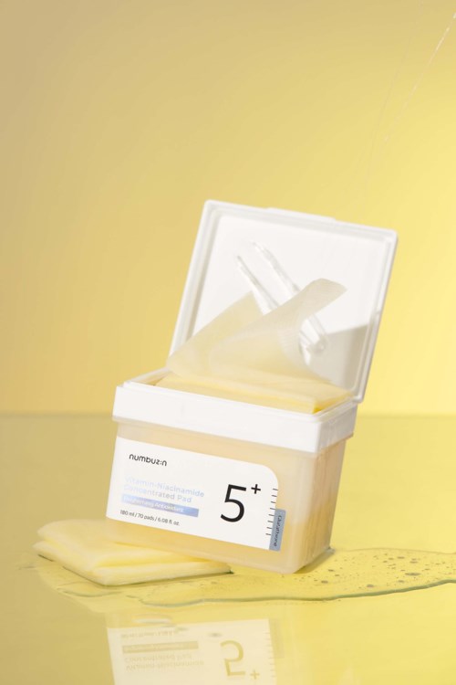 A box of disposable gloves, with some gloves outside the box, on a yellow surface and background.