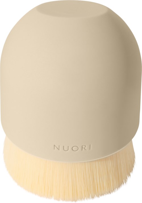 A beige, oval-shaped makeup brush with soft bristles and the brand name 'NUORI' on it.