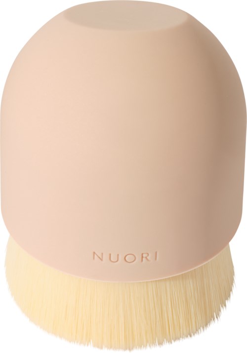 A soft, rounded makeup brush with a light pink handle and beige bristles. The brand name 'NUORI' is on the handle.