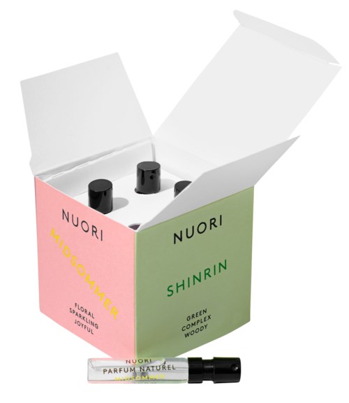 Two small black bottles inside a pink and green box. The box has text and the bottles likely contain perfume.