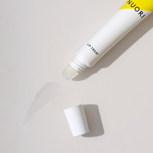 En vit tub märkta 'NUORI LIP TREAT' har sin kork borttagen och lite produkt syns på ytan.