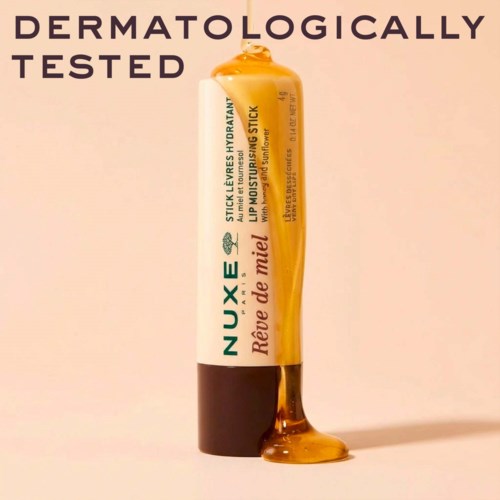 Läppbalsam i rör med gult gel, märkt NUXE, säger dermatologiskt testad och återfuktande.