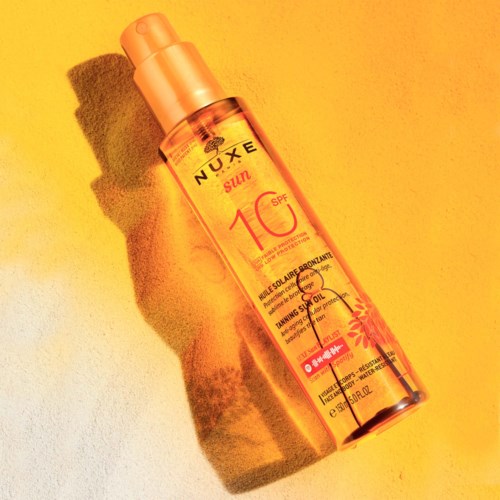 En solkrämssprayflaska med SPF 10, orange färg och solskyddsetikett på gul bakgrund.