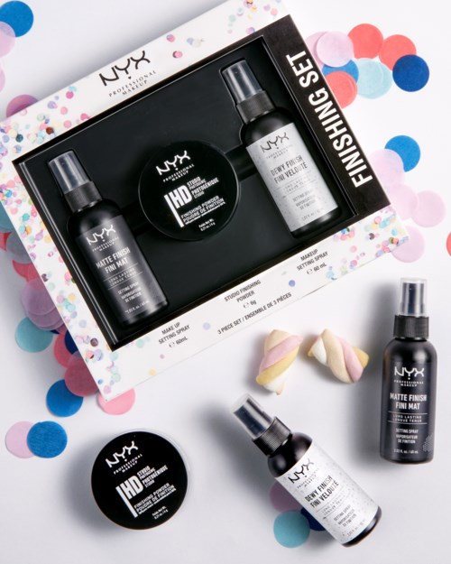 Et NYX makeup-innstilling spraysett med to sprayflasker og to små beholdere, omgitt av fargerikt konfetti og en sminksvamp.