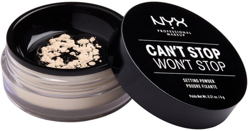 Open black container with light beige face powder inside, partially broken with powder pieces.