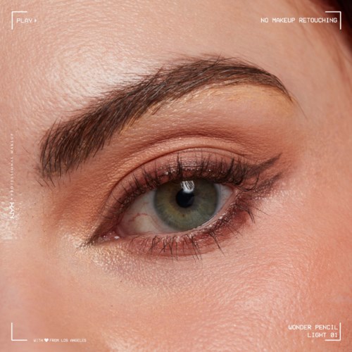 Close-up van iemands oog met make-up, groene iris en goed gedefinieerde wenkbrauw.