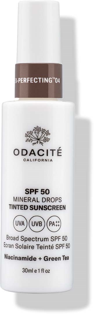 Vitt flaska med brun topp, märkt Odacité, solskydd med SPF 50, innehåller mineraldroppar, grönt te, bredspektrumskydd.
