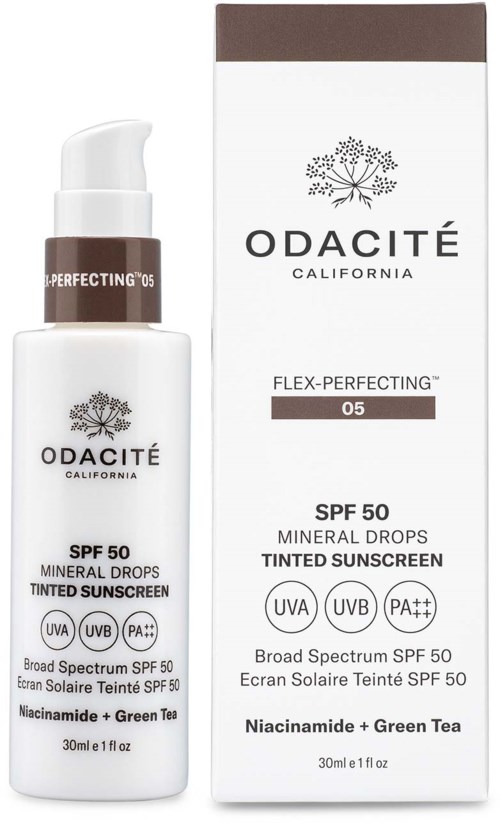 En hvit flaske og eske av Odacité tonet solkrem, SPF 50, med pumpe og etikett som viser UV-beskyttelse og grønn te.