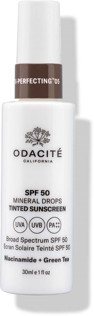 En hvit flaske med hvit pumpe og brun topp, merket Odacité California farget solkrem med SPF 50, Niacinamide og grønn te.